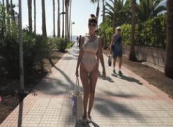 Caminando por la playa con su traje mojado y traslúcido